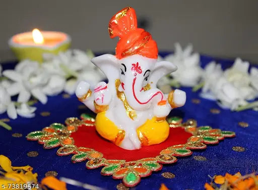 Ganesha statue with red cloth, yellow flower, and golden offerings