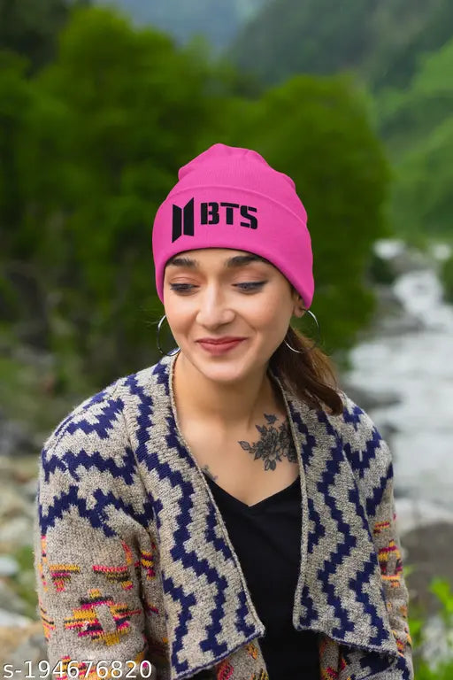 A pink embroidered woven hat with a black logo, featuring a person wearing it