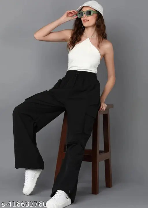 Black cargo pants with wide legs, pockets and drawstrings, sitting on a stool