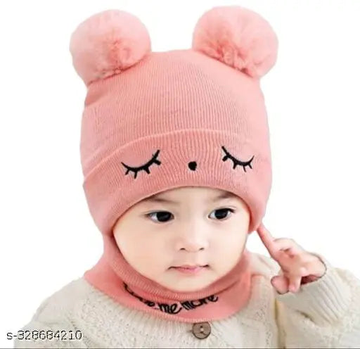 Baby wearing a pink beanie cap with bear ears and eyes, in front of plain white background