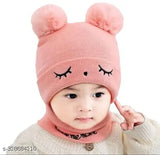 Baby wearing a pink beanie cap with bear ears and eyes, in front of plain white background