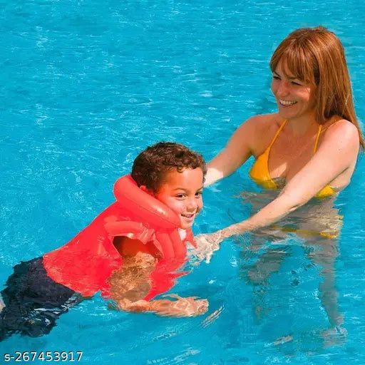 A child wearing a red life jacket, assisted in the water by an adult. This seems to be a swim vest designed for children's safety in the water. The life jacket is inflatable and features a bright color