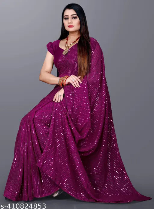 The image shows a woman in a vibrant purple saree with a glossy embroidered pallu, accessorized with what appears to be a red bindi on her forehead and red bangles on her wrists. She is wearing high-heeled shoes and has a traditional blouse piece paired with the saree