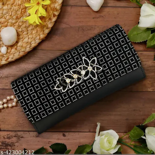 Black designer leather clutch with intricate embroidery and metal accent