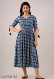 The image displays a person wearing a knee-length dress. It has short sleeves and a round neckline. The dress is in a deep blue color with a unique pattern, resembling traditional Indian attire
