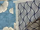 The image depicts a quilt with a dashing design of large blue and white leaves and flowers on a light background
