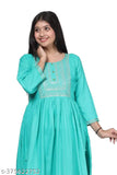 A woman in a vibrant turquoise long kurta with embroidery, standing against a white background