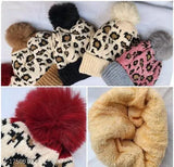 Striped knitted cap with pom pom on top, in shades of pink and red