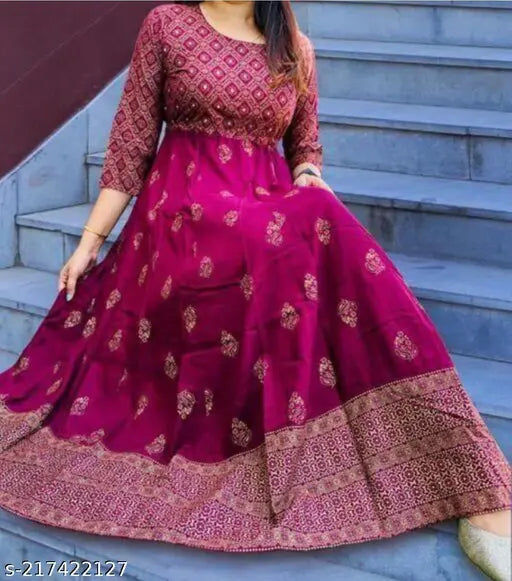 A woman is wearing a long, flowing, embroidered pink dress with a fitted waist