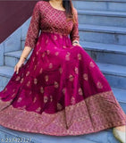 A woman is wearing a long, flowing, embroidered pink dress with a fitted waist