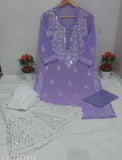 The image depicts a traditional Luckhnowi women's outfit, featuring a long chiffon kurta in shades of purple, adorned with intricate mirror work and detailed embroidery on both the inner style and the outer kurta. The ensemble is paired with matching sharara bottoms and inner styles, showcasing an elegant and feminine attire