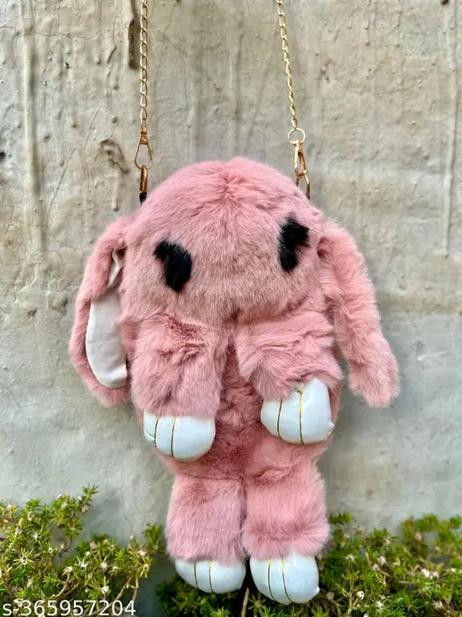 Pink plush toy with gold accents and black details, hanging on a chain