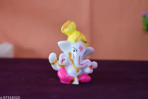 A white ceramic statue of a colorful elephant with trunk raised, wearing a pink hat and yellow glasses, adorned with red dots on table