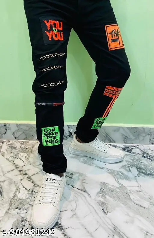 Fashionable men's black cotton blend jeans with slim fit, unique design, and 3 chains on right side leg. Sizes: 24, 26, 28, 30 (Waist 24-30in, Length 39in). Indian origin