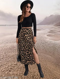 The image displays a person posing in front of a beach backdrop. They are wearing a casual, leopard print high-waist elastic single side slit skirt made from polyester blend material. The skirt has an elastic waistband and reaches 31 inches in length. The background suggests a coastal location, likely taken during the day due to the natural light. There is no visible text on the image indicating additional information or branding