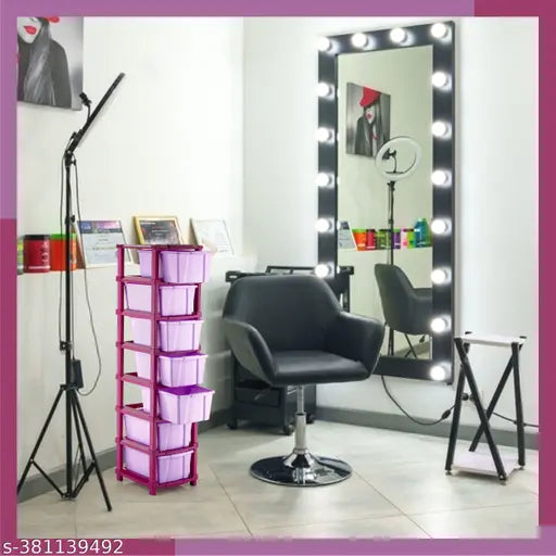 The image shows a multi-compartment desk organizer with a modern design, placed in an office room setting. It is made of transparent plastic and has various compartments for storage. The visible capacity of the containers suggests it is suitable for storing stationery or personal items
