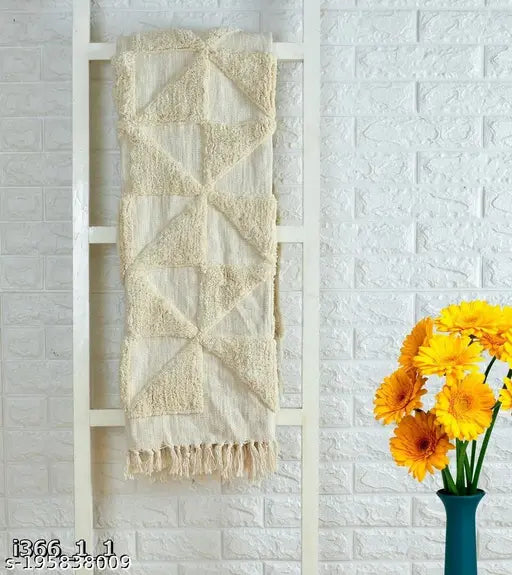 Trendy throw, beige and white geometric design, hanging on a white brick wall