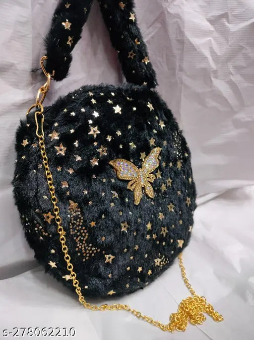 The image features a small, dark blue shoulder bag with multiple decorative elements, including stars and what appears to be a gold butterfly charm. It has a visible strap suggesting it is designed for carrying on one's shoulder or as a baby sling. There is no text or countable items in the image