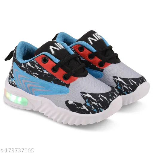 Blue, gray, and white boys' sports shoes. Lace-up design with red accents. Sole has a unique pattern. Includes Velcro straps for adjustable fit. Part of a collection for boys, perfect for active children. Comfortable for running or playing sports