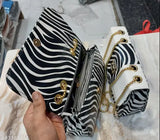 Black and white zebra print handbag with multiple pockets, strap closure