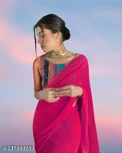 A woman in a pink sari with a dupatta over her shoulder, standing against a blue sky backdrop