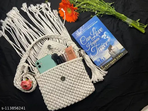 White macramé bag with tassels, holding book and phone