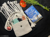 White macramé bag with tassels, holding book and phone
