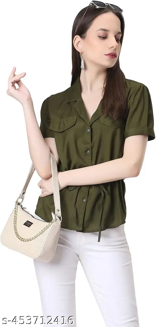 A woman wearing a casual olive green top stands against a plain background. She has short hair and is holding her hand on her hip. The sling bag in the image appears to be of an olive green hue, made from fabric with a fluffy texture resembling clouds. It features one main compartment and multiple smaller pockets, designed for travel essentials