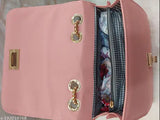 Pink and gold sling bag with zip closure, coin accents