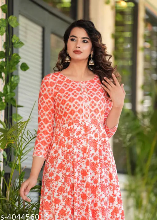 Orange rayon kurti with embroidered yoke, tassels, and long tiers. Vibrant Indian printed dress with three-quarter sleeves