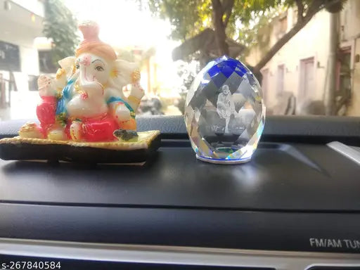 Crystal idol of Lord Saibaba with a checkered flag pattern, placed on a car's dashboard, small size