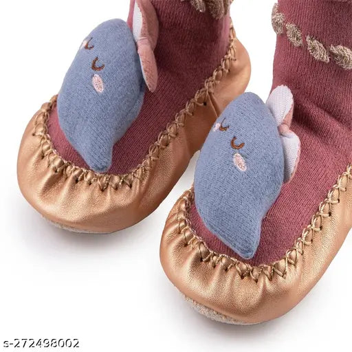 The image shows a pair of pink, soft children's shoes with blue trim and a light blue teddy bear motif. They have an anti-skid sole, are breathable, and designed for kids aged 6 months to 2 years