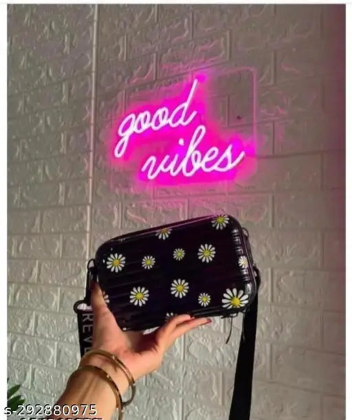Purple mini suitcase-style sling bag with side pockets. Cosmetic box accessory for girls. Small black floral design purse