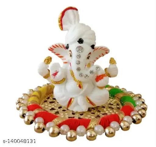 White porcelain Ganesh statue with a plated palte and brass Akhand LotusKamal deepak. Decorative brass crystal oil lamp with an unlit wick. Puja decor