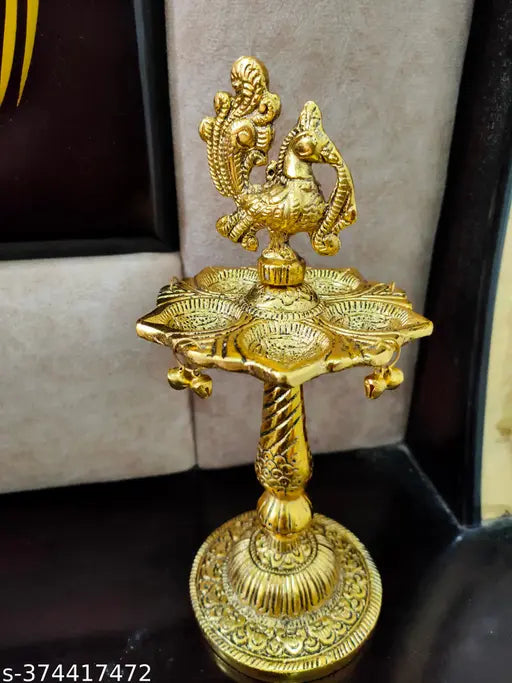 Golden peacock designer metal diya stand, intricately detailed Indian metalwork on display