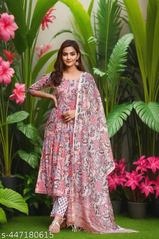 A woman in a vibrant floral patterned kurta set with a matching dupatta, posing outdoors