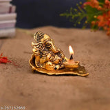 Metal Ganesh statue with diya, gold-toned home decor or gifting item. Intricately carved Hindu deity figurine with diya holders and bells, 3cm high. Indian origin