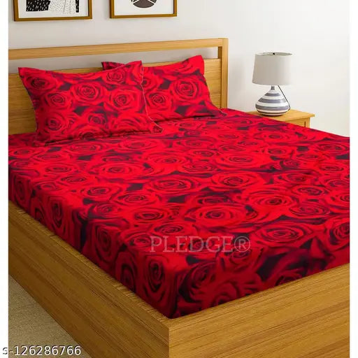 A red king-size bed with a cream-colored wooden frame, topped with four matching red pillows and covered with a comforter featuring a rose pattern. The image has the watermark "PLEDGE CREATIONS