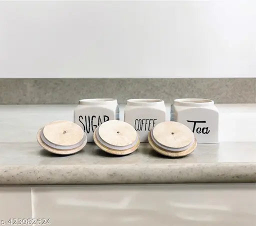 Tea, coffee, and sugar canisters on countertop in kitchen setting. Set includes three ceramic kitchen airtight storage canisters