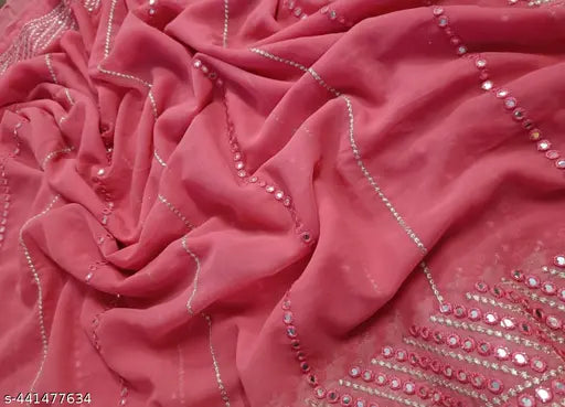 The image shows a vibrant red sari adorned with sequin details and embellishments. It features a pallu, which is the decorative end of the garment, and is paired with a matching blouse, suggesting it's a complete outfit. The sari has a zari work, which is a traditional Indian embroidery technique using gold and silver threads, adding to its luxurious look. The background appears to be a soft, neutral color that contrasts with the sari, highlighting its colors and design