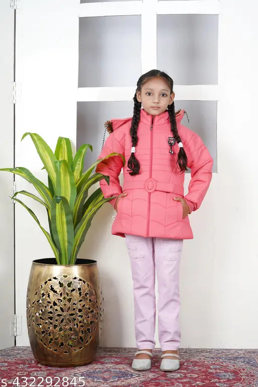 A young girl in a pink jacket and white pants, posing indoors