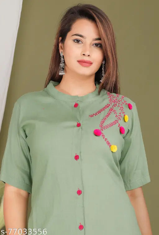 This is an image of a woman wearing a vibrant green kurta. The kurta features decorative embroidery with red and yellow flowers, adding a touch of festivity to the overall look. The sleeves of the kurta are three-quarter length, and it appears to be a full-length garment that reaches down to mid-calf