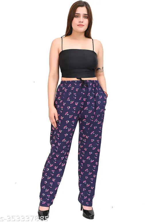 A person wearing a black top with a floral pattern, posing in pants