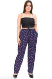 A person wearing a black top with a floral pattern, posing in pants
