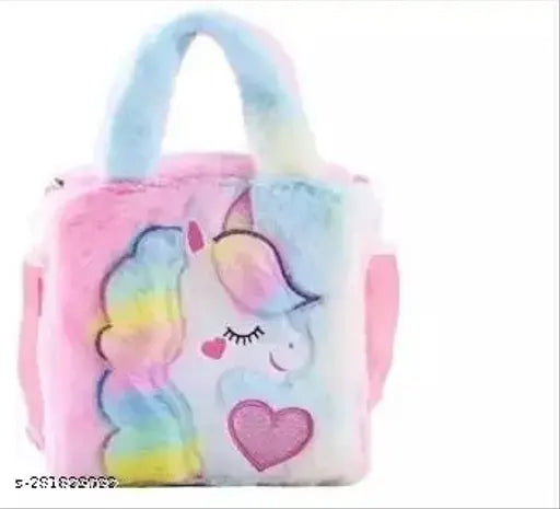 The image displays a pastel pink unicorn-themed handbag with a prominent illustration of a cartoon unicorn on it. The handbag features a zip closure and has a multicolored rainbow stripe design on the strap, as well as the body showcasing the unicorn figure in different colors of the rainbow