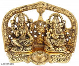The image displays a traditional Indian murti of Lord Ganesha and Goddess Laxmi, featuring intricate gold detailing, in a decorative style. The murti is adorned with a lit diya