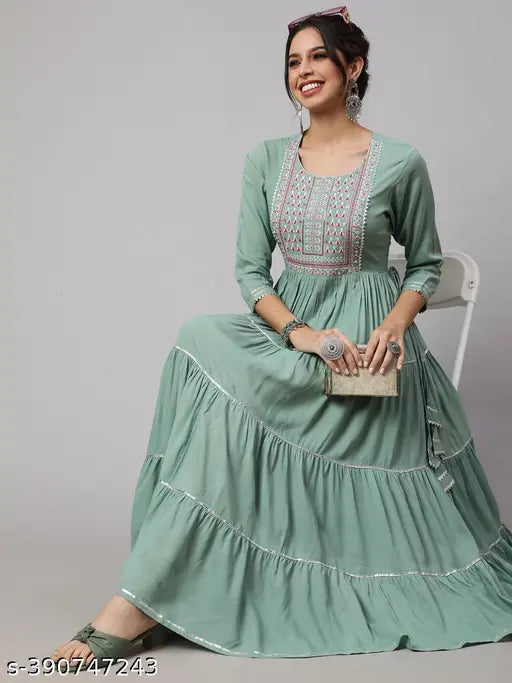 A woman sitting on a chair wearing a long sleeved, rayon embroidered, round neck kurta with ruffled ankles