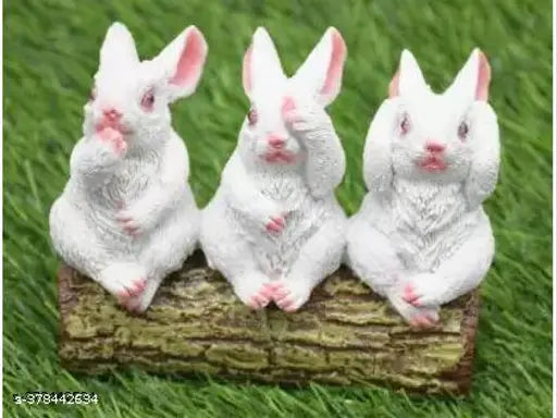 A set of three white rabbit figurines on a tree trunk table top
