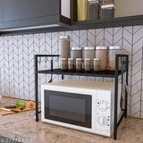 The microwave is placed on a black, metallic storage stand in a modern kitchen