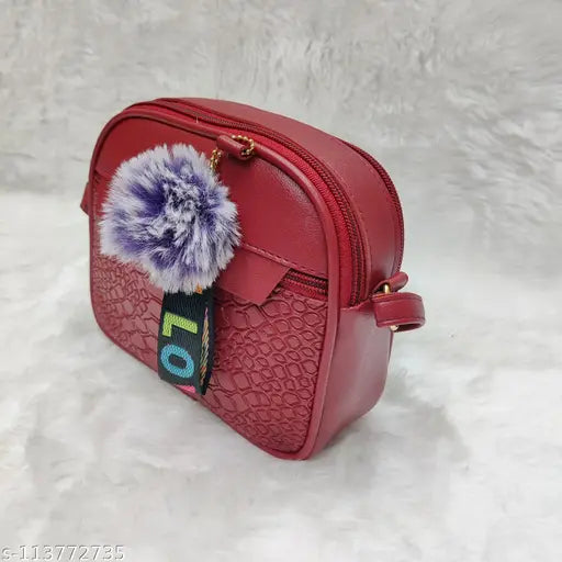Purple pompom on a red faux leather sling bag